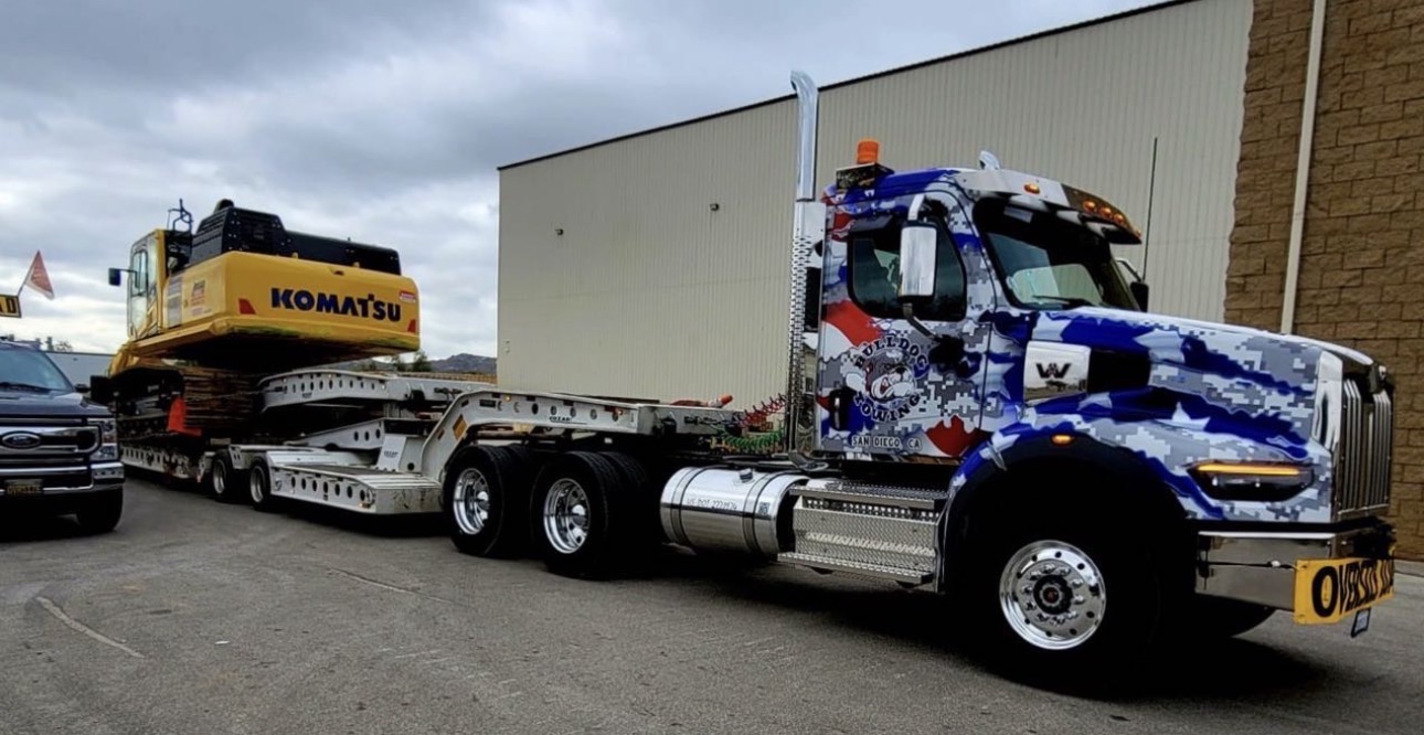 Bulldog Towing transporting large construction equipment using specialized heavy-haul trailers.